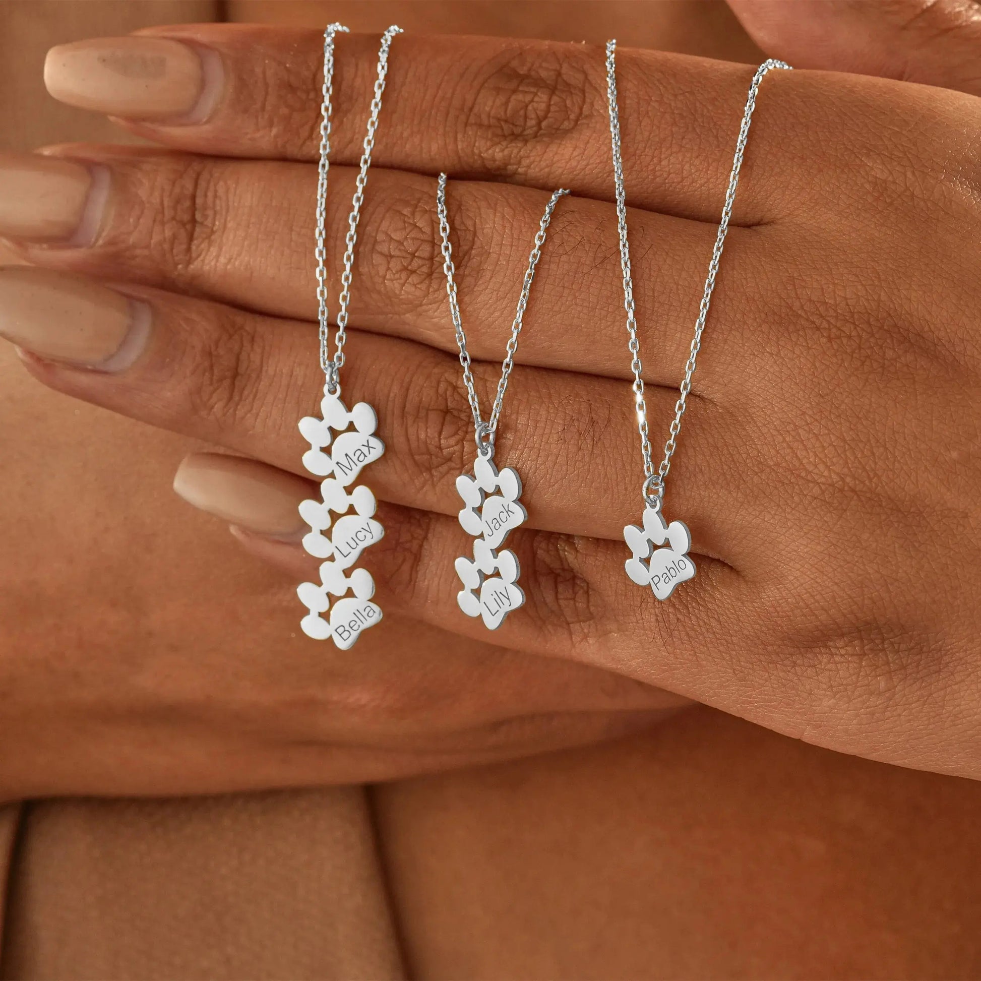 Close-up of engraved paw print pendant on dainty necklace — waterproof everyday jewelry