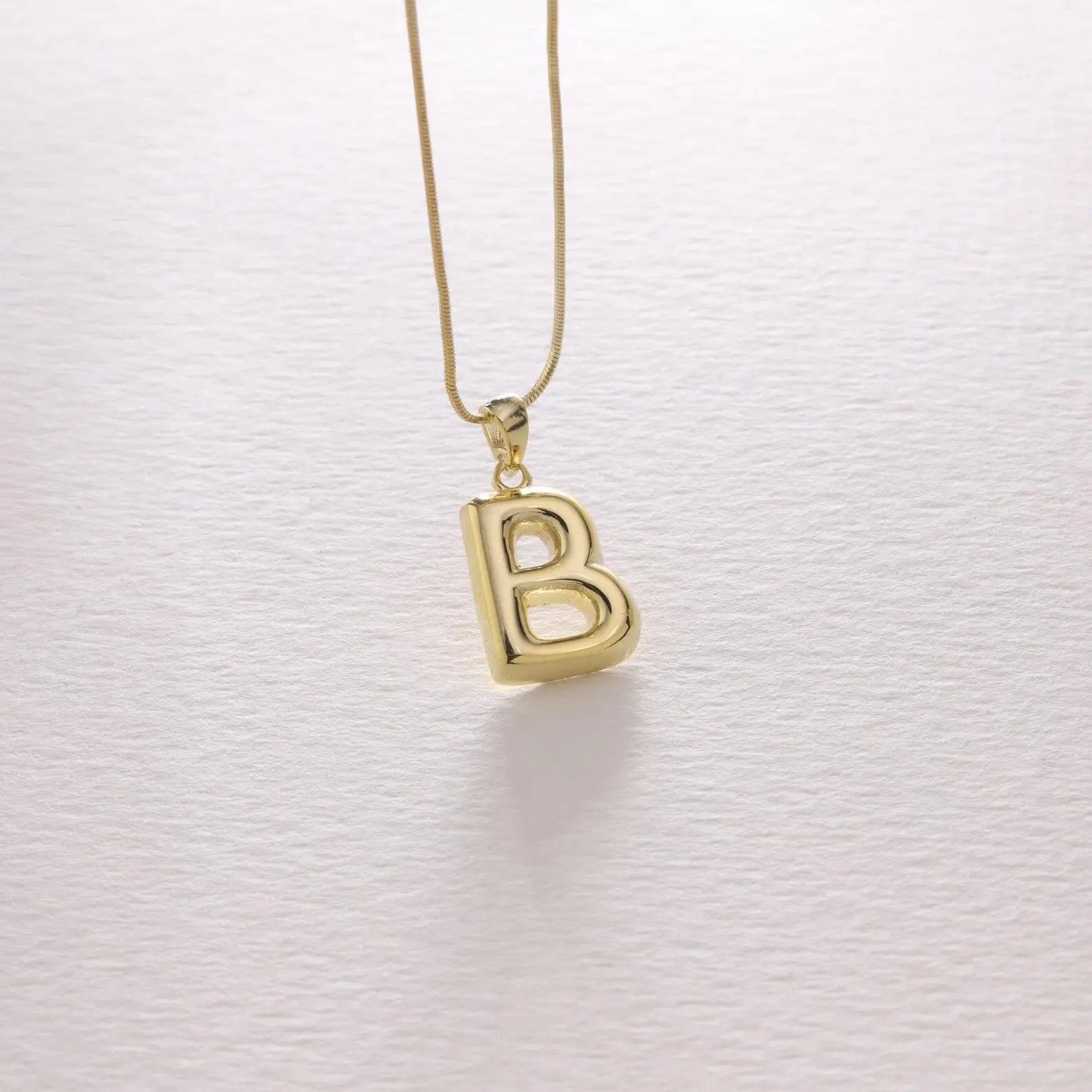 Bubble letter necklace in gold styled with casual outfit — bold personalized statement jewelry
